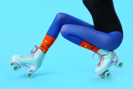 Legs of woman in roller skates on blue background