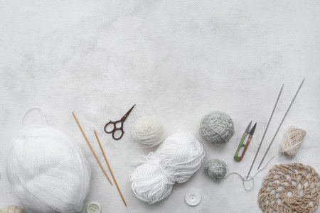 Knitting needles, yarn balls and scissors on white background