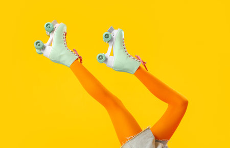 Legs of woman in roller skates on yellow background