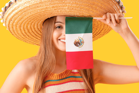 Young woman in sombrero hat with Mexican flag on yellow background, closeupの写真素材