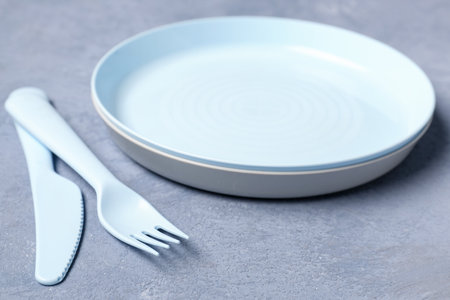 Plate with knife and fork for baby on grunge blue backgroundの写真素材