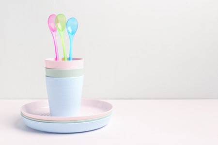 Plates with spoons and cups for baby on white tableの写真素材