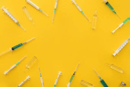 Frame made of medical syringes and ampoules on yellow backgroundの写真素材