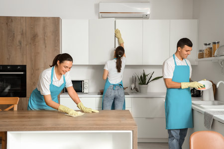 Young janitors cleaning in kitchenの写真素材