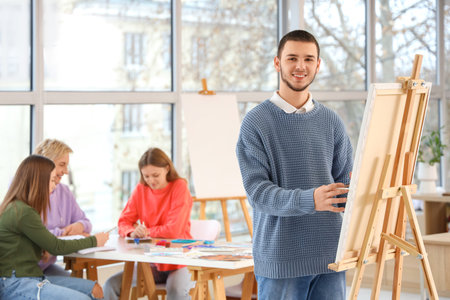 Male student painting on canvas in art schoolの写真素材