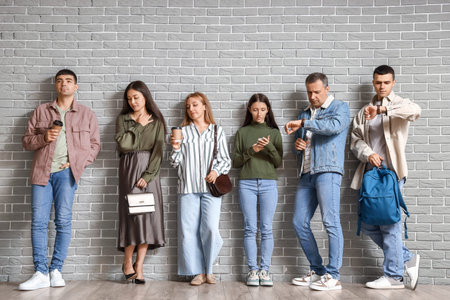 People waiting in line near gray brick wall