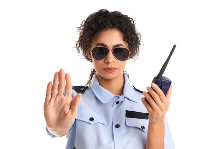 African-American female police officer with radio transmitter showing stop gesture on white...