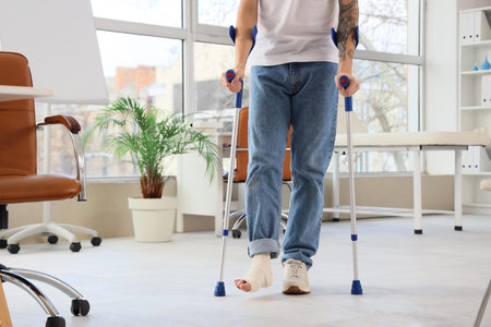Injured young man after accident with crutches walking in clinic