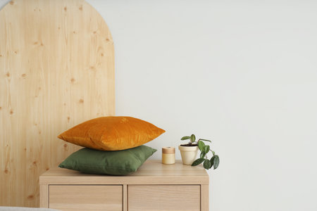 Chest of drawers with soft pillows near white wallの写真素材
