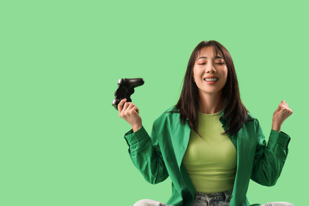 Happy Asian woman holding gamepad on green background