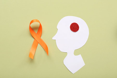 Paper human head and orange ribbon on green background. Multiple Sclerosis Awareness Monthの写真素材