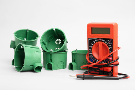 Set of socket boxes and multimeter on light background
