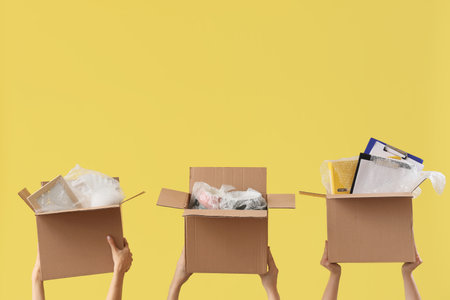 Women with moving boxes on yellow backgroundの写真素材