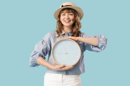 Happy young woman with clock on blue backgroundの写真素材