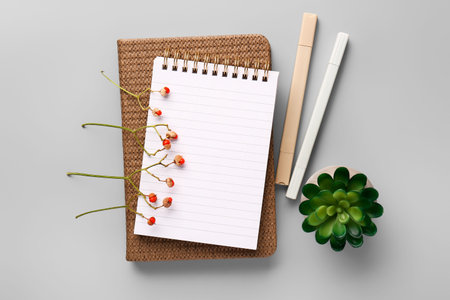 Notebook, stationery and dried flowers on gray background