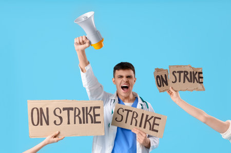 Protesting male doctor with megaphone and placards on blue background. Strike conceptの写真素材