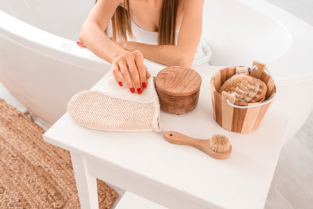 Young woman with massage glove and accessories on table taking bath at home, closeupの写真素材