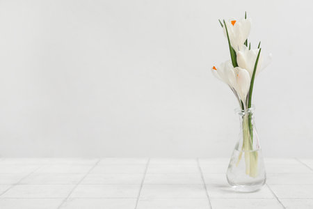 Glass vase with beautiful crocus flowers on white tile tableの写真素材