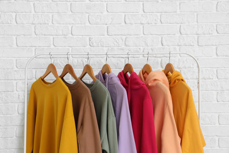 Rack with warm female clothes near light brick wall, closeupの写真素材