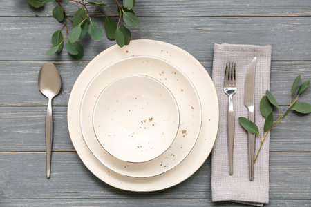 Beautiful table setting with leaves on gray wooden background