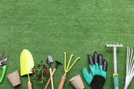 Tools for gardening and plant in pot on green grass background. Top viewの写真素材