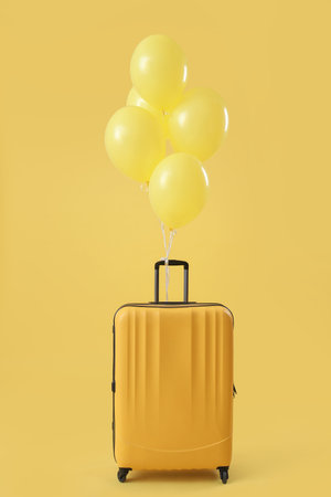 Suitcase with floating balloons on yellow backgroundの写真素材