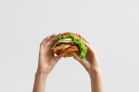Female hands with tasty burger on white backgroundの写真素材