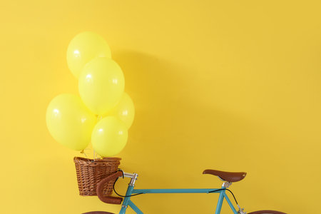 Bicycle with balloons in basket on yellow backgroundの写真素材