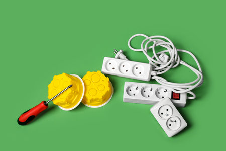 Extension cords, electrical junction boxes and screwdriver on green backgroundの写真素材