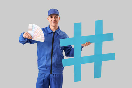 Handsome male painter with palette samples and hashtag sign on gray backgroundの写真素材