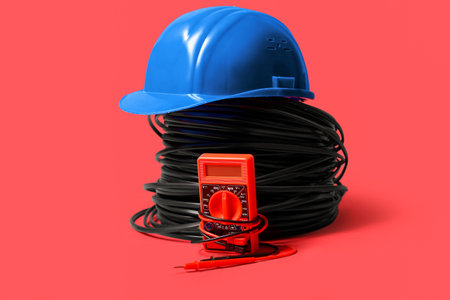 Multimeter, cables and hardhat on red backgroundの写真素材