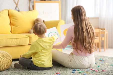 Female psychologist showing smiles to little boy in office, back view. World Autism Awareness Dayの写真素材