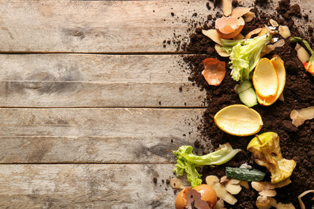 Organic waste and soil on wooden background. Compost recycling concept