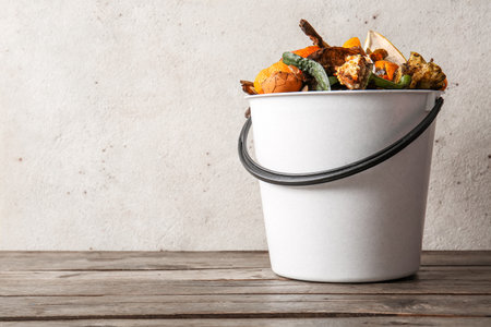 Bucket with organic waste on wooden table. Compost recycling conceptの写真素材