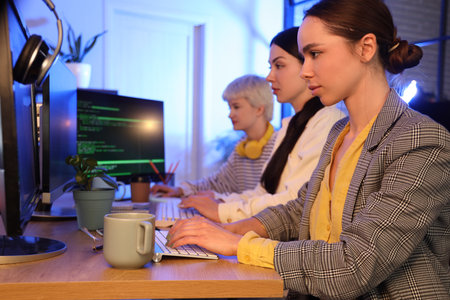 Team of female programmers working in office at nightの写真素材