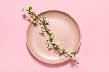 Beautiful plate with blossoming branch on pink backgroundの写真素材