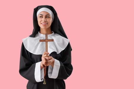 Young nun with cross and beads on pink backgroundの写真素材