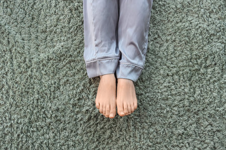 Barefoot woman on green carpet at home, top viewの写真素材