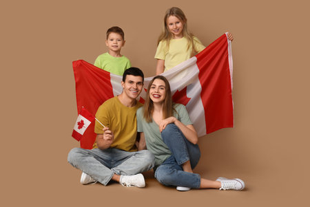 Happy family with flags of Canada sitting on brown backgroundの写真素材