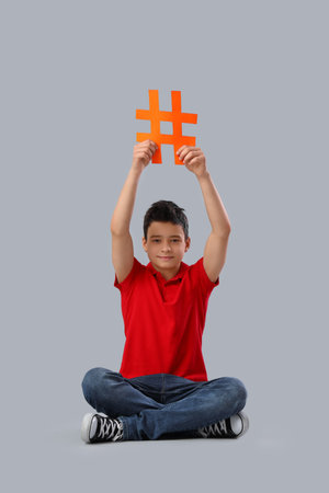 Cute teenage boy with hashtag on gray backgroundの写真素材
