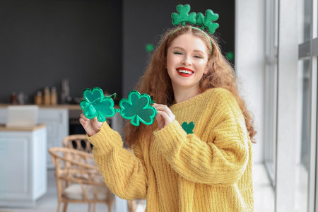 Young woman with decorative eyeglasses celebrating St. Patrick's Day at homeの写真素材