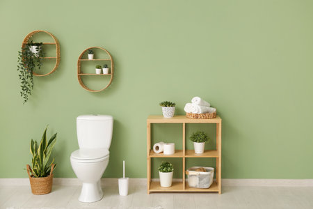 Interior of stylish bathroom with houseplants and ceramic toilet bowl near green wallの写真素材