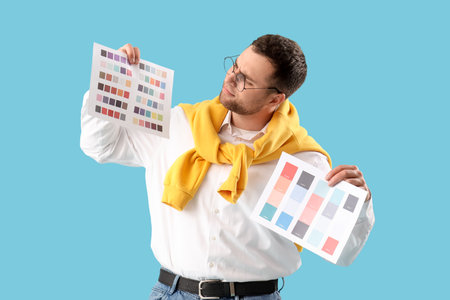Male designer with paint color palettes on blue backgroundの写真素材