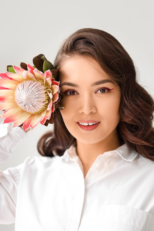 Young Asian woman with beautiful protea flower on white backgroundの写真素材