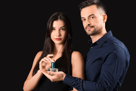 Young couple with perfume on dark backgroundの写真素材