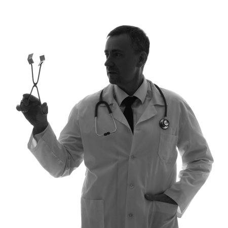 Silhouette of mature doctor with surgical forceps on white backgroundの写真素材