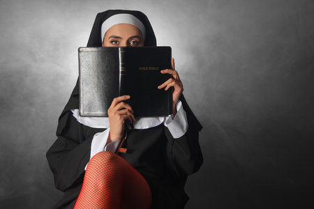 Naughty nun with Holy Bible and smoke on dark backgroundの写真素材