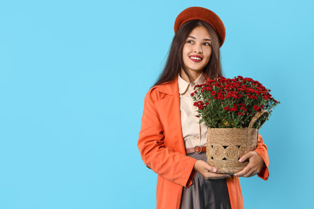 Young Asian woman with chrysanthemum flowers on blue backgroundの写真素材