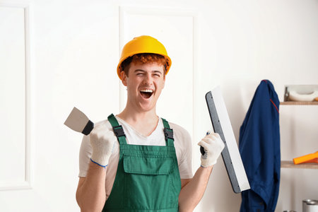 Male decorator with putty knives working in roomの写真素材
