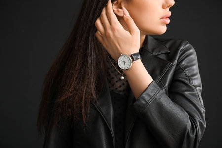 Stylish beautiful woman with wristwatch on black backgroundの写真素材